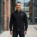Man wearing a black shirt with a logo standing in an urban setting